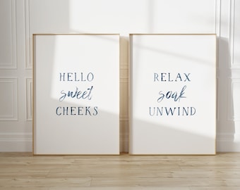May include: Two framed prints with blue watercolor text. The left print says "Hello sweet cheeks" and the right print says "Relax soak unwind".