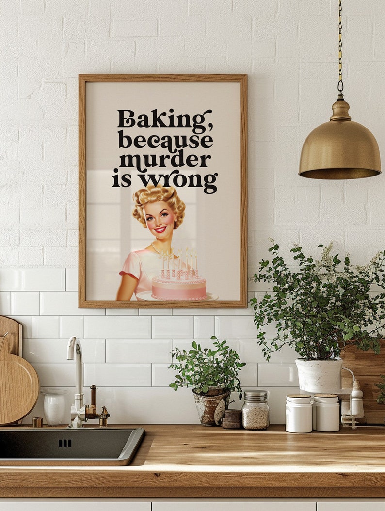 Peut inclure: Une impression encadr&eacute;e avec une illustration r&eacute;tro d'une femme tenant un g&acirc;teau rose avec des bougies. Le texte sur l'impression dit "Baking, because murder is wrong."