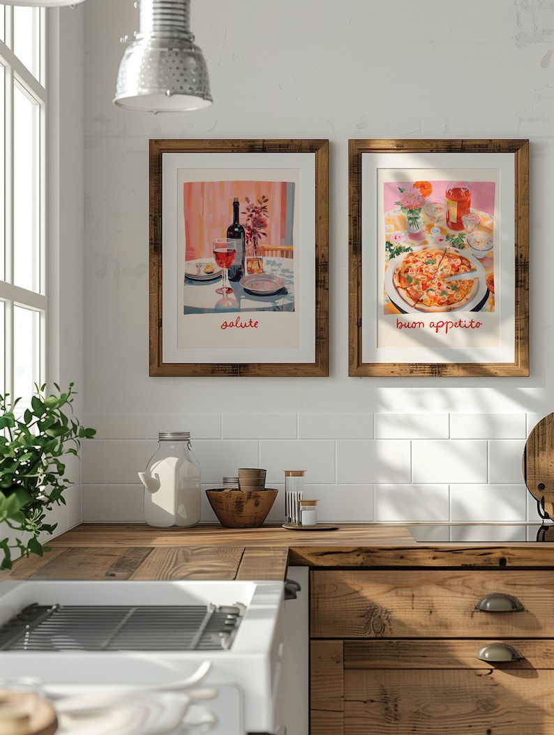 May include: Two framed prints hanging on a white tiled wall in a kitchen. The print on the left shows a glass of red wine and a bottle of wine on a table with the word "salute" written below. The print on the right shows a pizza with the words "buon appetito" written below.