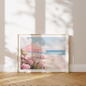 May include: A framed painting of a beach scene with pink umbrellas and lounge chairs. The beach is white sand and the ocean is blue. There are pink flowers in the foreground.