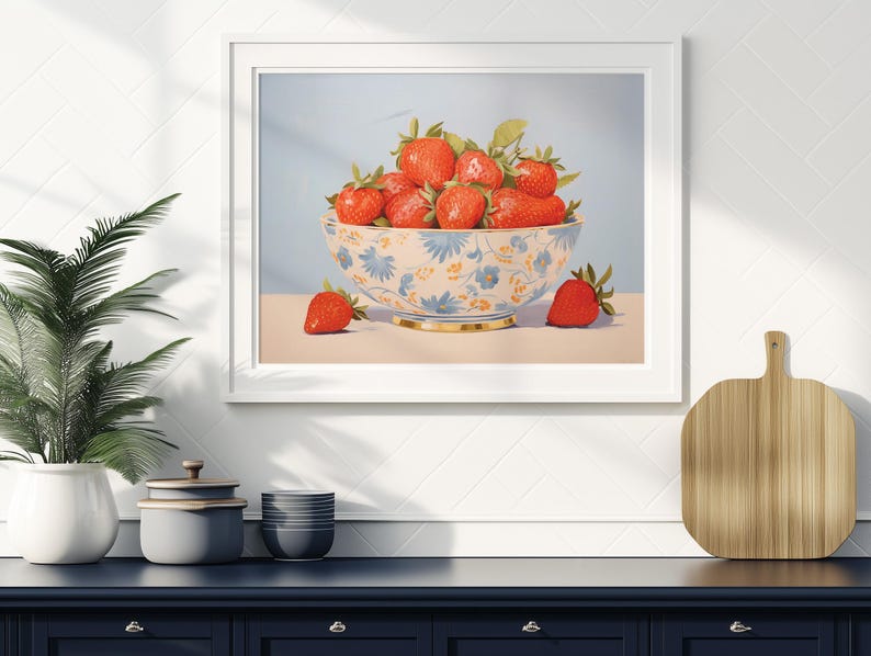 Op de afbeelding: Een witte kom met een blauw en geel bloemenpatroon gevuld met rode aardbeien. De kom staat op een lichtblauwe ondergrond met een enkele aardbei ervoor.