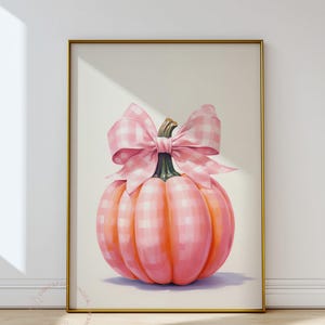 Puede incluir: Impresi&oacute;n enmarcada que presenta una calabaza rosa con un gran lazo de cuadros. La calabaza es de color rosa suave con sombras anaranjadas, y el lazo tiene un dise&ntilde;o a cuadros rosa y blanco. El fondo es neutro.