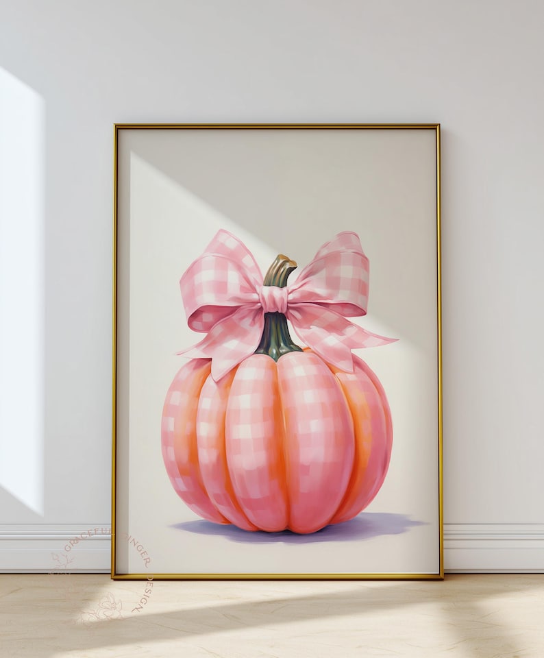 Puede incluir: Impresi&oacute;n enmarcada que presenta una calabaza rosa con un gran lazo de cuadros. La calabaza es de color rosa suave con sombras anaranjadas, y el lazo tiene un dise&ntilde;o a cuadros rosa y blanco. El fondo es neutro.