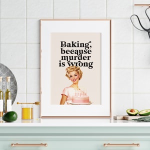 Peut inclure: Une impression encadr&eacute;e avec une illustration r&eacute;tro d'une femme tenant un g&acirc;teau rose avec des bougies. Le texte sur l'impression dit "Baking, because murder is wrong."