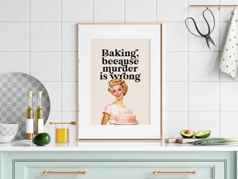 Peut inclure: Une impression encadr&eacute;e avec une illustration r&eacute;tro d'une femme tenant un g&acirc;teau rose avec des bougies. Le texte sur l'impression dit "Baking, because murder is wrong."