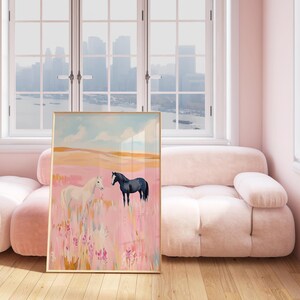 May include: A framed painting of two horses in a field. The horse on the left is white and the horse on the right is black. The field is pink and has a blue sky in the background.