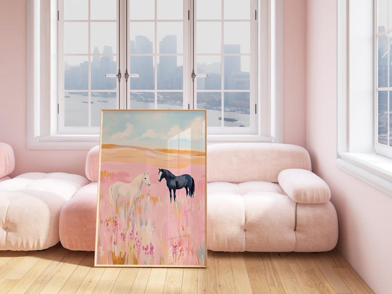 May include: A framed painting of two horses in a field. The horse on the left is white and the horse on the right is black. The field is pink and has a blue sky in the background.