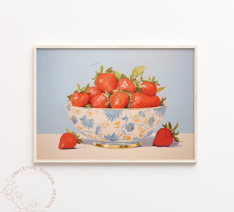 Op de afbeelding: Een witte kom met een blauw bloemenpatroon gevuld met rode aardbeien. De kom staat op een lichtblauw oppervlak met een enkele aardbei ervoor.