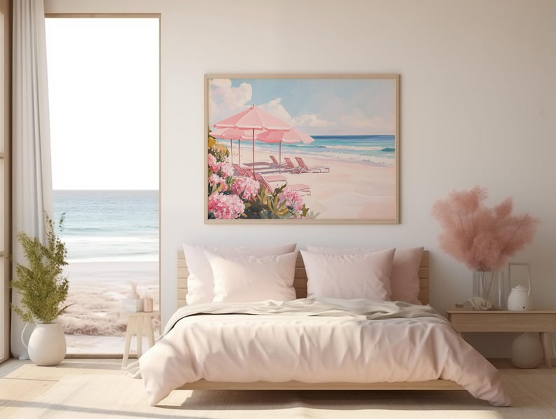 Coastal-themed beach print displayed above a soft pink bed in a light-filled bedroom. The artwork features pink umbrellas and flowers beside tranquil turquoise waters, echoing the serene ocean view just outside the open door.