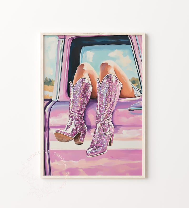 May include: A framed print of a woman's legs and sparkly pink cowboy boots hanging out of a pink car window. The boots have a high heel and are covered in glitter. The background shows a blue sky and a field.