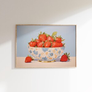 Op de afbeelding: Een blauwe en witte kom met bloemenpatroon gevuld met rode aardbeien. Twee extra aardbeien liggen op de tafel naast de kom.