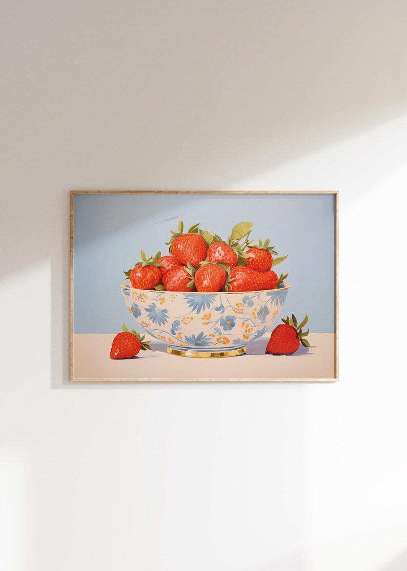 Op de afbeelding: Een blauwe en witte kom met bloemenpatroon gevuld met rode aardbeien. Twee extra aardbeien liggen op de tafel naast de kom.