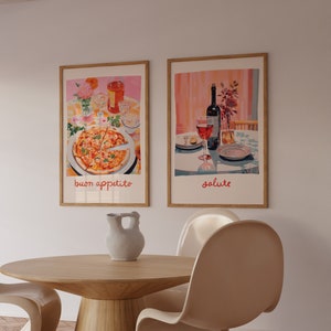 May include: Two framed prints on a white wall, one depicting a pizza with the text "buon appetito" and the other depicting a bottle of wine and two glasses with the text "salute". A wooden table with a ceramic pitcher and two white chairs are in the foreground.