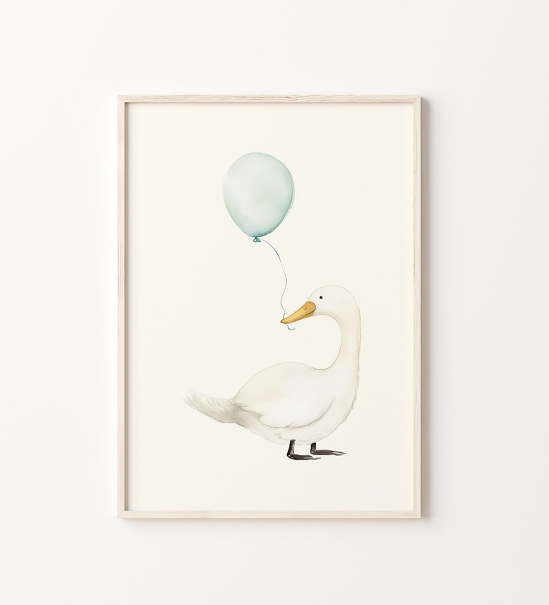 May include: Watercolor illustration of a white duck with a yellow beak, holding a light blue balloon. The artwork is framed in a light wood frame, perfect for a nursery or children's room. The background is a soft, off-white color.