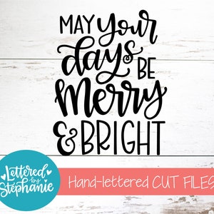 May include: Black and white hand-lettered design on a white wood background. The design says "May your days be merry & bright".