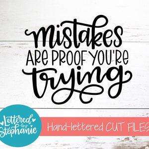May include: Black and white hand-lettered quote on a white wood background. The quote reads "Mistakes are proof you're trying". The image also includes a logo for "Lettered by Stephanie" in a teal circle.