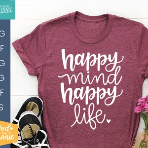 May include: A maroon t-shirt with the text "happy mind happy life" in white cursive lettering.