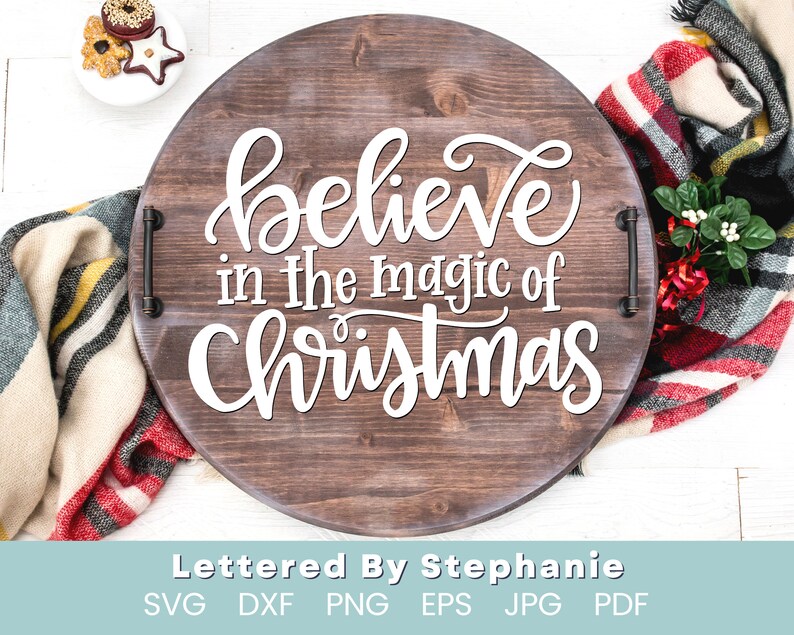 May include: A wooden round tray with a white inscription that reads "believe in the magic of Christmas". The tray has metal handles on the sides.