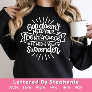 Puede incluir: Sudadera negra con texto blanco: "Dios no necesita tu desempeño, Él necesita tu entrega". El diseño incluye líneas decorativas y una pancarta. En la imagen se sostiene una taza blanca. La parte inferior de la imagen tiene el texto "Lettered By Stephanie".
