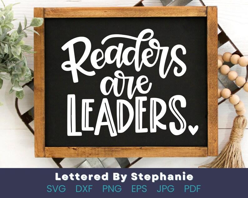 May include: A black chalkboard with a wooden frame displays the text "Readers are Leaders" in white cursive lettering with a small heart at the end.