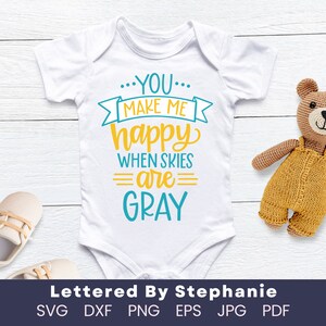 Peut inclure: Combinaison blanche pour bébé avec un texte bleu et jaune qui dit "...YOU... MAKE ME happy WHEN SKIES =are= GRAY". Lettered By Stephanie est écrit sous la combinaison.