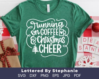 Op de afbeelding: Groen T-shirt met witte tekst die "Running on Coffee & Christmas Cheer" luidt. De tekst is in een feestelijk, handschriftlijk lettertype. Een klein kerstboompictogram is opgenomen in het ontwerp.