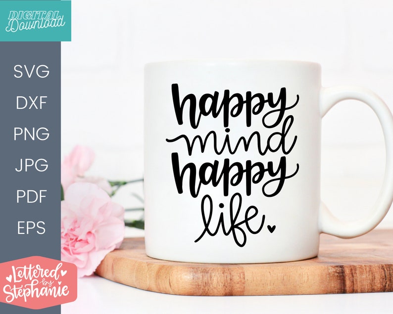 May include: White ceramic mug with black text that reads "happy mind happy life." The mug is sitting on a wooden surface.