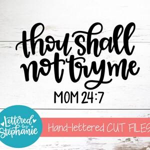 May include: Black and white hand-lettered design on a white wood background. The design says "Thou shall not try me MOM 24:7".