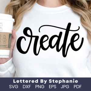 Peut inclure: Un t-shirt blanc avec le mot "create" écrit en lettres cursives noires. Le texte est centré sur le t-shirt. Le t-shirt est porté par une personne tenant une tasse de café.