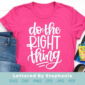 May include: Pink t-shirt with the text "do the RIGHT thing" in white lettering. The shirt is laying on a white surface with a pair of blue jeans and a box of crayons.