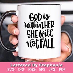May include: White ceramic mug with a black handle. The mug has black text that reads "GOD is within HER SHE will not FALL". The text is in a handwritten style font. The mug is being held by a person's hand.