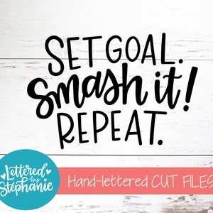May include: Black and white hand-lettered design on a white wood background. The design reads "Set Goal. Smash it! Repeat."