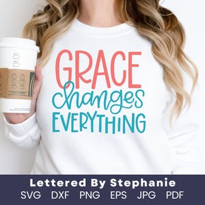 May include: White long-sleeved shirt with the text "GRACE changes EVERYTHING" in pink and blue lettering.