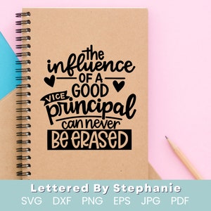 May include: A brown notebook with a spiral binding and a black quote that reads "The influence of a good vice principal can never be erased". The quote is surrounded by hearts. The notebook is on a pink surface.