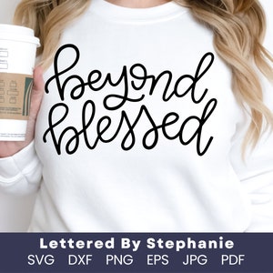 May include: A white sweatshirt with the text "Beyond Blessed" written in black cursive script. The text is centered on the sweatshirt. The sweatshirt is being worn by a person.