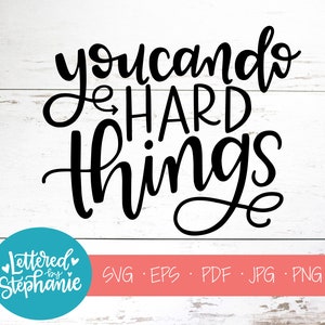 May include: Black and white calligraphy text on a white wood background. The text reads "You can do hard things".
