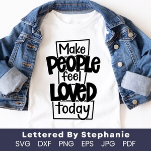 以下が含まれることがあります： 「Make PEOPLE feel LOVED today」の黒い文字がプリントされた白いTシャツ。青いデニムジャケットと組み合わせています。画像の下部には「Lettered By Stephanie」とファイルタイプの略語も表示されています。