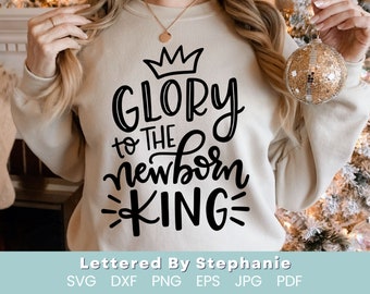 May include: A beige sweatshirt with a black graphic design that reads "Glory to the newborn King" with a crown above the word "Glory".