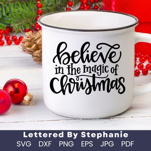 May include: White ceramic mug with a black rim and handle. The mug has a black handwritten design that says "believe in the magic of Christmas".