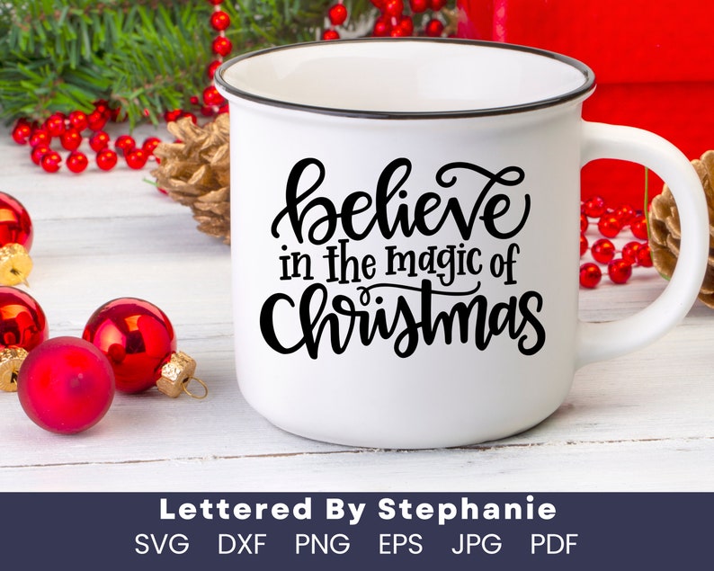 May include: White ceramic mug with a black rim and handle. The mug has a black handwritten design that says "believe in the magic of Christmas".