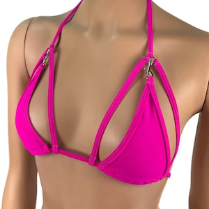 Op de afbeelding: Een felroze bikini top met een halterband en meerdere banden over de voorkant. De banden hebben zilveren metalen gespen.