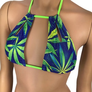 May include: A blue halter top with a green cannabis leaf pattern. The top has a neon green trim and straps. The fabric has a sparkly finish. The top is designed with cut-out sections.