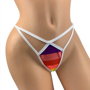 May include: A thong-style bikini bottom with a rainbow striped front panel. The bikini bottom has a white elastic waistband and straps. The rainbow stripes include purple, pink, red, orange, and yellow.