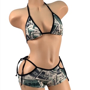 May include: Black and green bikini set with a money print pattern. The top is a triangle style with adjustable straps. The bottom is a cheeky style with a cutout on each side and ties on the sides.