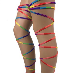 May include: Rainbow colored leg wraps made of elastic cord. The wraps are tied around the legs in a criss-cross pattern.