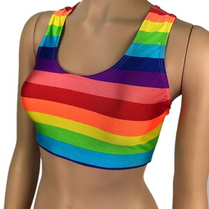 May include: A rainbow striped crop top with a scoop neck and racerback straps. The top is made of a stretchy, shiny fabric.