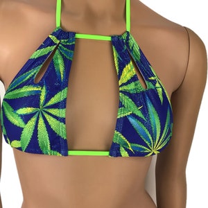 May include: A blue bikini top with a cannabis leaf pattern in green and yellow. The top has a halter neck and neon green trim. The design features a cutout in the center.