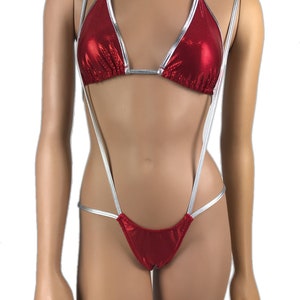 Puede incluir: Bikini rojo con ribete plateado. La parte superior halter y la parte inferior están conectadas por finas correas plateadas. El bikini está hecho de un material brillante y texturizado.