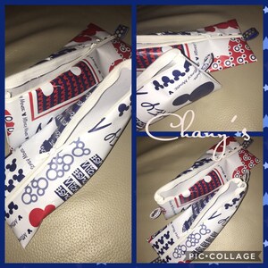 Könnte beinhalten: Weiße Federmäppchen mit Reißverschluss, verziert mit sich wiederholenden Mustern von Mickey Mouse Silhouetten, Herzen und geometrischen Formen in Rot und Blau. Die Mäppchen haben eine kleine Schlaufe.