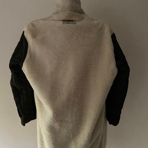 Puede incluir: Una chaqueta marr&oacute;n, blanca y negra con forro polar. La chaqueta tiene un cuello alto y una cremallera.